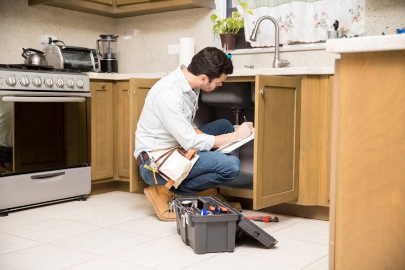 Why is my garbage disposal humming? Man inspecting garbage disposal